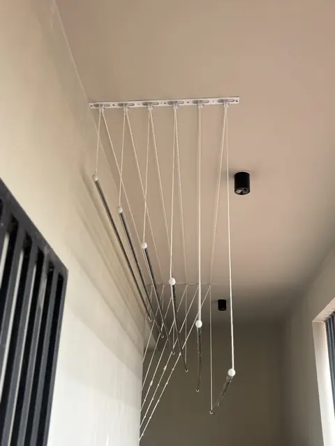 Stainless steel ceiling cloth hanger rods hanging from the ceiling of a utility area