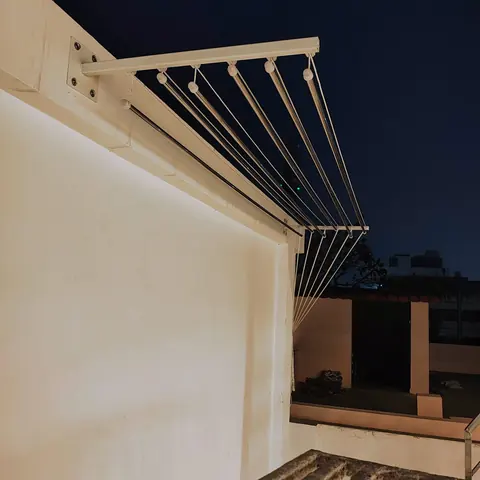 A wall mount cloth hanger fixed to a terrace wall, rods folded out